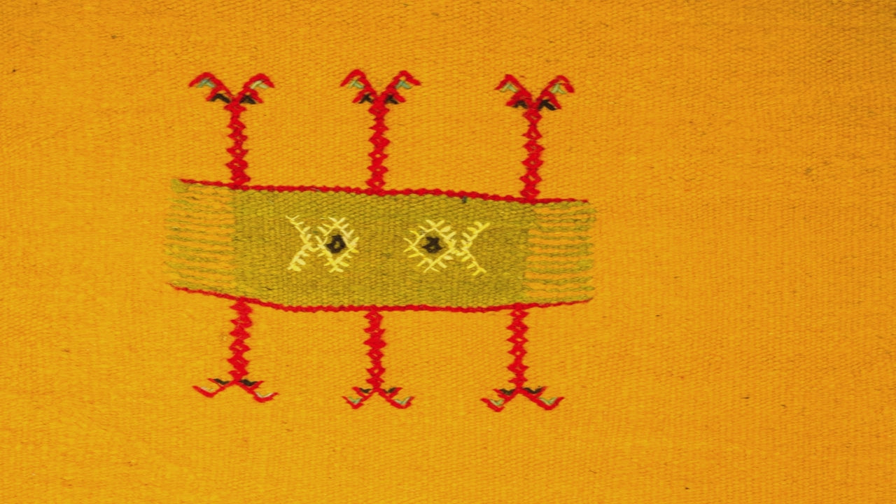 close-up video of a yellow moroccan rug handwoven with hand embroidered tribal motif
