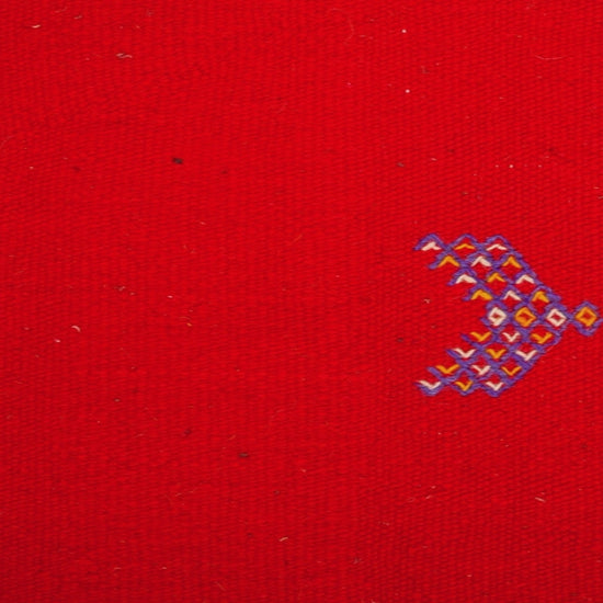 close up video of a red moroccan rug handwoven with hand embroidered tribal motifs